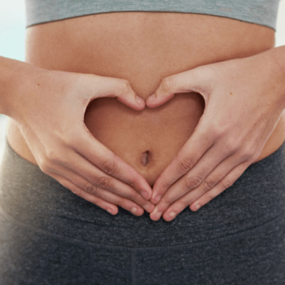 Mujer formando corazón sobre el abdomen, salud intestinal y bienestar vegano